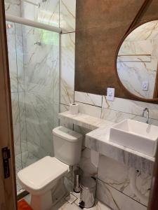 uma casa de banho com um WC, um lavatório e um espelho. em Suites Abraão Beach em Abraão