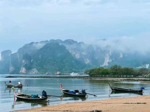 Tres barcos en el agua con montañas en el fondo en VILLA LOVED BEACH AO NAM MAO krabi en Ao Nam Mao