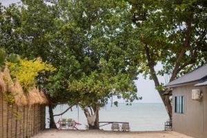 a table and chairs under a tree next to the ocean at VILLA LOVED BEACH AO NAM MAO krabi in Ao Nam Mao