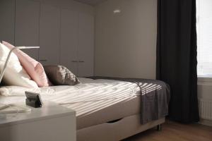 a bedroom with a bed with pink pillows on it at Modern apartment with Sauna, near Transit Hub/Dixi in Vantaa