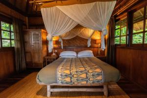 1 dormitorio con 1 cama con dosel en Sarinbuana Eco Lodge, en Blimbing