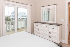 een slaapkamer met een dressoir, een spiegel en een balkon bij Villas View in North Topsail Beach