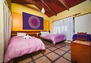 1 Schlafzimmer mit 2 Betten mit rosa Bettwäsche und einem Gemälde in der Unterkunft Hospedaje Chaska Pisac in Pisac