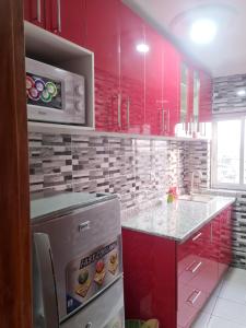 a kitchen with red cabinets and a counter top at Résidence Sighaka - Suite Royale - WiFi, Gardien, Parking in Douala