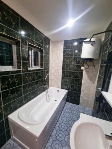 a bathroom with a tub and a toilet and a sink at Résidence Sighaka - Suite Royale - WiFi, Gardien, Parking in Douala