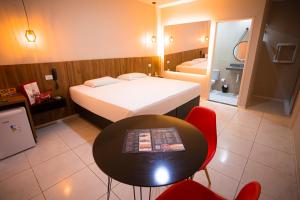 Lotus Motel Guaribas في أرابيراكا: غرفة نوم بسرير وطاولة وكراسي
