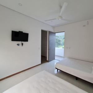 a white room with a bed and a flat screen tv at La Higuera, Casa Campestre. in El Asilo