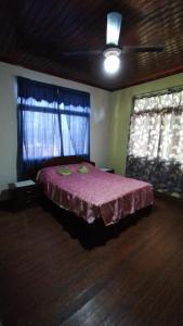 1 dormitorio con 1 cama con colcha rosa y 2 ventanas en Revivir "LA CASA DE LOS ABUELOS" en Montecarlo