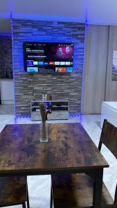 mesa de madera con sillas y TV en la pared en Relax & Chill en Sevran