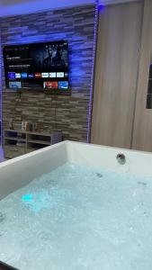 a tub filled with water with a tv in a room at Relax & Chill in Sevran