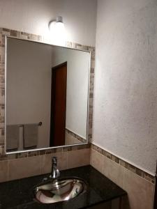 baño con lavabo y espejo grande en Casa de Montaña en Yacanto