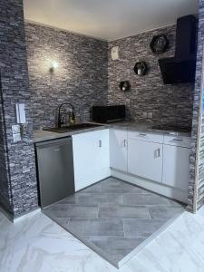 a kitchen with white cabinets and a brick wall at Relax & Chill in Sevran