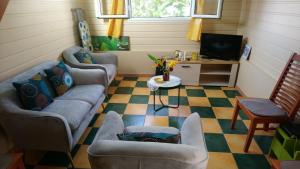 a living room with two couches and a tv at Zénitude Bungalow in Le Lorrain