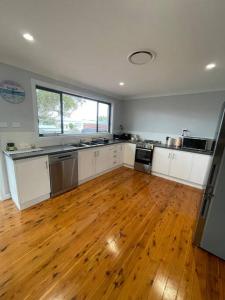 a kitchen with white cabinets and a hard wood floor at Bayview at Callala in Callala Bay
