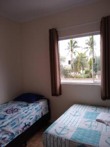 um quarto com 2 camas e uma janela em Pousada do Chileno na Praia Grande