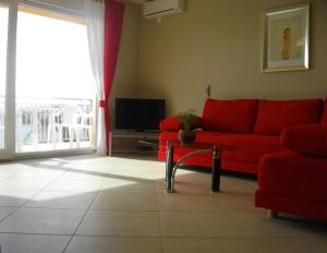 a living room with a red couch and a tv at Luna Apartments in Trogir