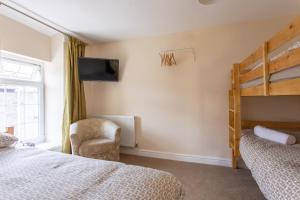 a bedroom with two beds and a tv and a chair at Bikehaus@The Colliers Arms in Abercanaid