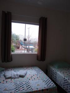 a bedroom with a bed and a window with a view at Pousada do Chileno in Praia Grande