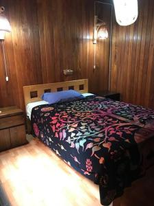 a bed in a bedroom with wooden walls and wooden floors at La Casa Roja Cerro Azul in Cerro Azul