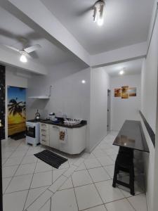 a kitchen with a counter and a table in it at APARTAMENTO COQUEIROS A 1 QUADRA DO MAR in Guaratuba