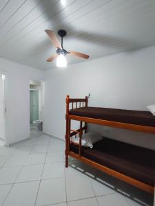 a room with a ceiling fan and a bed at APARTAMENTO COQUEIROS A 1 QUADRA DO MAR in Guaratuba