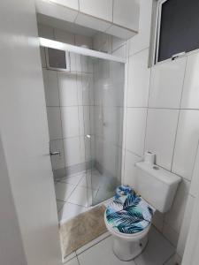 a bathroom with a toilet and a glass shower at APARTAMENTO COQUEIROS A 1 QUADRA DO MAR in Guaratuba
