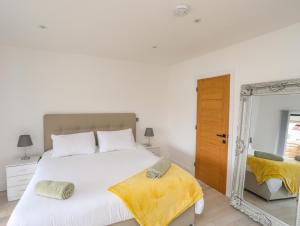 a white bedroom with a large bed and a mirror at Bryn Min Manton Bach in Caernarfon
