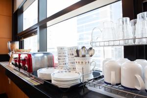 a kitchen counter with plates and utensils on a shelf at K-Grand Hostel Dongdaemun in Seoul