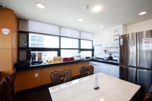 a kitchen with a white table and a refrigerator at K-Grand Hostel Dongdaemun in Seoul