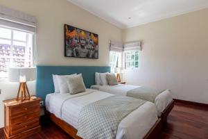 a bedroom with two beds and a painting on the wall at Palm Villa A Paradise for Families and Friends in Sanur in Sanur