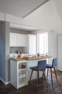 a white kitchen with two chairs and a counter at Reetdorf Geltinger Birk Atelierhaus Schilfinsel in Nieby