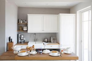 una cocina con armarios blancos y una mesa de madera con platos en Reetdorf Geltinger Birk Atelierhaus Schilfinsel, en Nieby