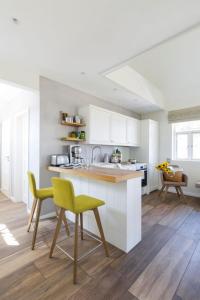 a kitchen with white cabinets and a yellow chair at Reetdorf Geltinger Birk Malerhaus Eichenwald in Nieby
