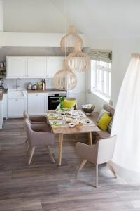 a kitchen with a wooden table and chairs in a room at Reetdorf Geltinger Birk Malerhaus Eichenwald in Nieby +16 photos