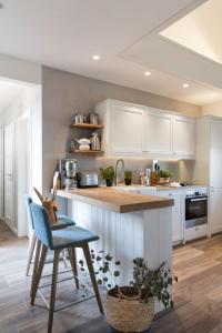 a kitchen with white cabinets and a blue chair at Reetdorf Geltinger Birk Künstlerkate Eisvogel in Nieby