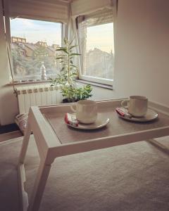 two coffee cups sitting on a table in front of a window at Apartman K2 in Žarkovo