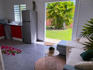 una cucina con frigorifero e un divano in soggiorno di Logement paisible jacuzzi jardin privatif climatisation a Baie-Mahault