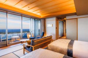 a hotel room with two beds and a balcony at KAMENOI HOTEL Izukogen in Ito
