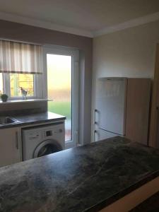 a kitchen with a counter and a refrigerator and a window at 1 bedroom apartment with parking. in Great Wakering