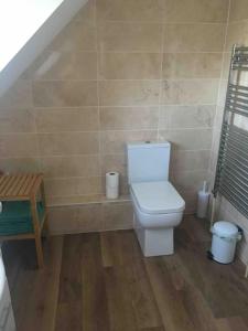 a bathroom with a toilet and a wooden floor at 1 bedroom apartment with parking. in Great Wakering