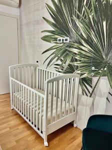 2 lits bébés blancs dans une chambre avec un palmier dans l'établissement Villa con giardino in piena città, à Modène