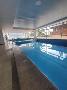 een groot zwembad met blauw water in een gebouw bij invitin annabella's apartment in Quito