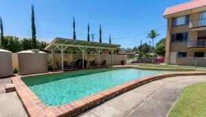 a swimming pool with a gazebo next to a building at Aqua on Bribie 100 metres to Beach and Shops in Bongaree