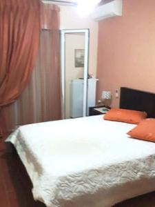 1 dormitorio con 1 cama con sábanas blancas y almohadas de color naranja en Vicky's house en Mirina