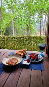 a table with two plates of food and a glass of wine at Cabana Retrô com lareira e Ofurô em Monte Verde in Monte Verde
