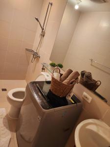 a bathroom with a toilet and a sink with baskets at Minimalist Condo in Azure North in San Fernando