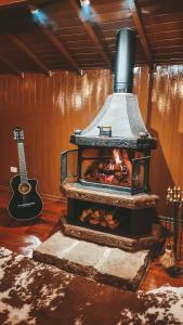 a woodburning stove in a room with a guitar at Cabana Retrô - Forest Place in Monte Verde