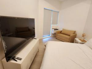 a bedroom with a large flat screen tv and a couch at Minimalist Condo in Azure North in San Fernando