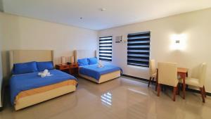 Un dormitorio con dos camas y una mesa y sillas. en Grand Emilia Hotel, en Cebú