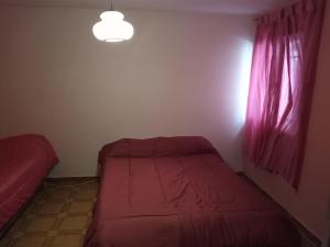 House Ramblon في سان لويس: غرفة نوم بها سرير ونافذة بها أغطية وردية